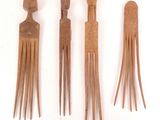 three wooden hair combs are lined up on a white surface