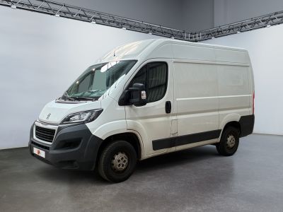 La camionnette blanche est garée dans une grande pièce au sol gris.