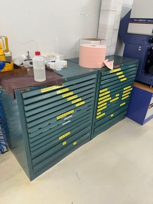 une armoire verte avec de nombreux tiroirs et une machine bleue