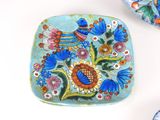 a blue plate with a bird and flowers on it