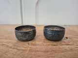 two bowls sitting on a wooden table with a white wall in the background