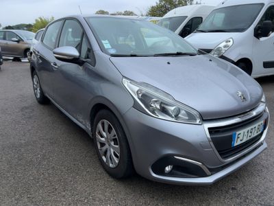 La voiture grise est garée sur le parking, à côté d'autres voitures.