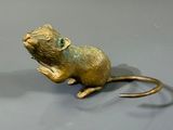 statue d'une souris assise sur ses pattes arrière sur une surface grise