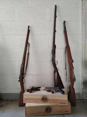 Deux armes sont posées sur une caisse en bois dans une pièce.