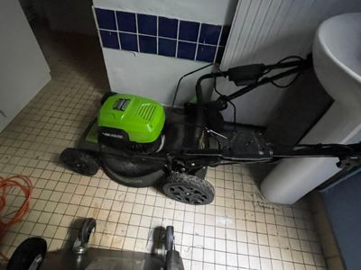 une tondeuse à gazon verte posée par terre à côté d'un évier