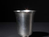 a silver cup sitting on a table with a black background