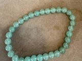 un gros plan d'un bracelet en perles posé sur une table à côté d'un sac