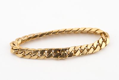 gros plan d'un bracelet en or sur fond blanc