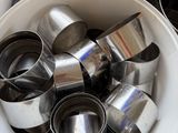 a white bucket filled with metal measuring cups and measuring spoons