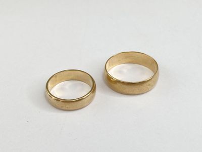 two gold wedding rings on a white surface