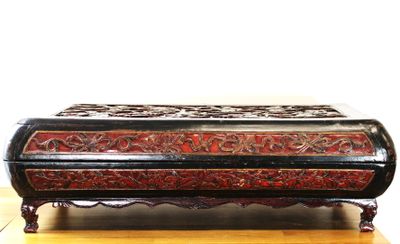 une boîte noire et rouge posée sur une table en bois
