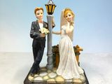 figurines of a bride and groom standing next to a street light
