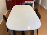 une table et des chaises blanches dans une cuisine aux placards rouges