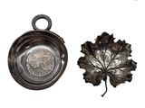 une assiette en argent ornée d'une feuille, posée à côté d'un bol en argent