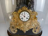 a clock that is under a glass case on a table