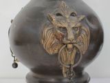 a bronze vase with a lion head on it