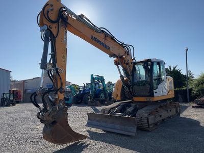 the back end of a yellow and black excavator parked in a parking lot