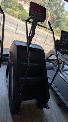 two tread machines in a gym room with a car in the background