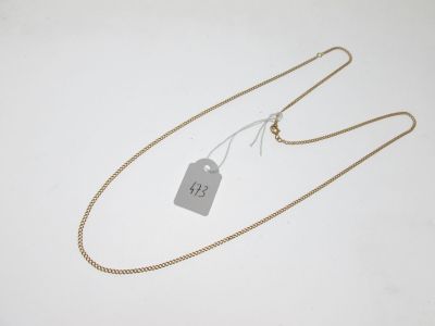 a gold chain with a tag attached to it on a white surface