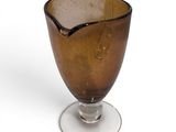 a glass cup with a spoon in it on a white surface