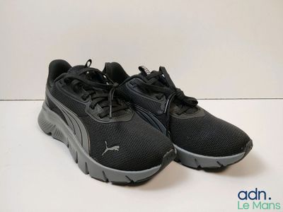 une paire de baskets noires posées sur une surface blanche