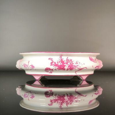 a white bowl with pink flowers on it on a table