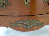 a wooden chest of drawers with brass decorations on it