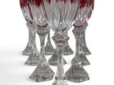 six red wine glasses are lined up in a row on a white surface