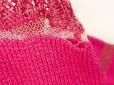close up of a pink knitted sweater with a hole in the middle