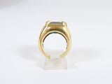 a close up of a gold ring with a green stone in it