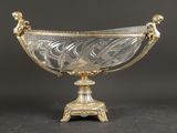 un bol ancien en argent et en verre posé sur un socle, sur fond noir