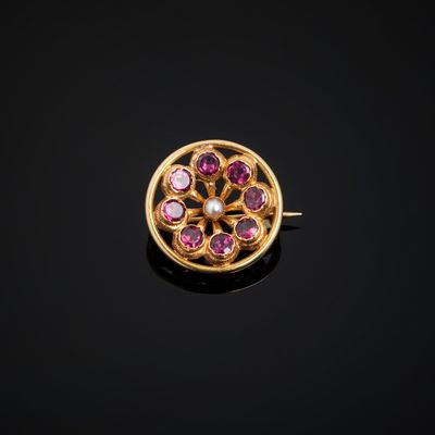 a close up of a gold ring with pink stones on a black surface