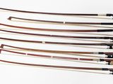 Plusieurs types d'archets de violon sont disposés sur une surface blanche