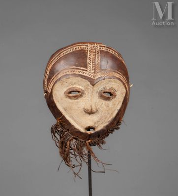 a wooden mask on a stand with a brown and white face