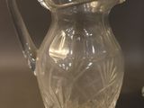 a glass pitcher sitting next to a glass cup