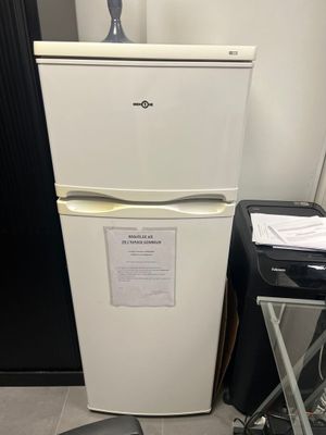 a white refrigerator with a sign on it next to a chair