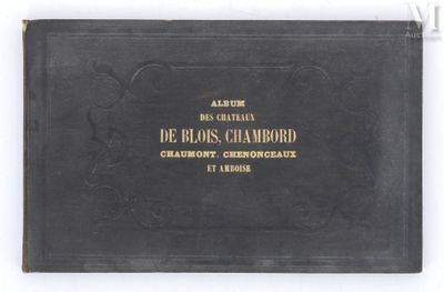 an old black book with gold lettering sitting on top of a white table