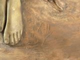 a bronze statue of a woman with her feet on the ground