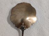 une cuillère en argent ornée d'une fleur sur une surface blanche