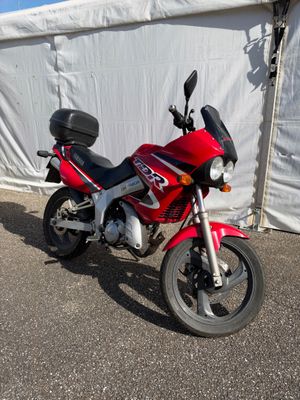 une moto rouge garée devant une tente blanche
