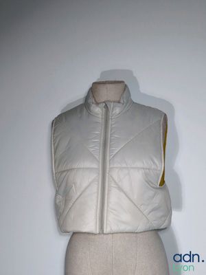 a white vest on a mannequin with a yellow zipper
