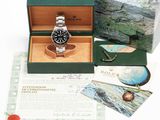 a rolex watch in a box with a brochure in the background