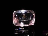 a close up of a pink diamond on a black surface