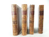 three old books sitting on top of each other on a white surface