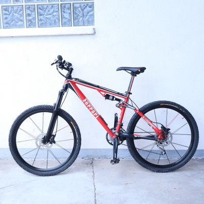 un vélo rouge et noir garé contre un mur blanc