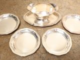 four silver plates and a saucer on a table