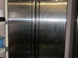 two stainless steel refrigerators in a kitchen next to a shelf