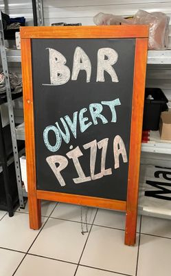 une pancarte indiquant « Bar Overt Pizza » posée par terre