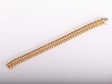 gros plan d'un bracelet en or sur une surface blanche