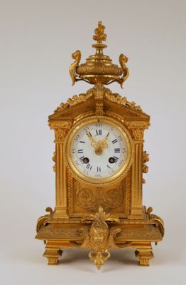 a gold clock with a bird on top of it